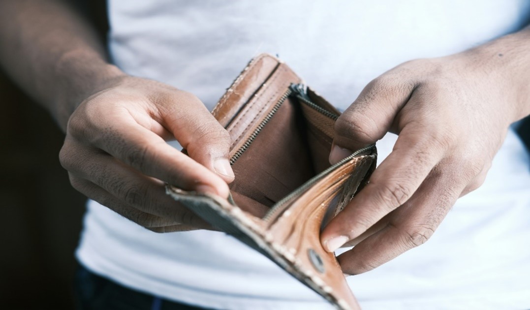 Image of a man opening his wallet and there is no money in there.