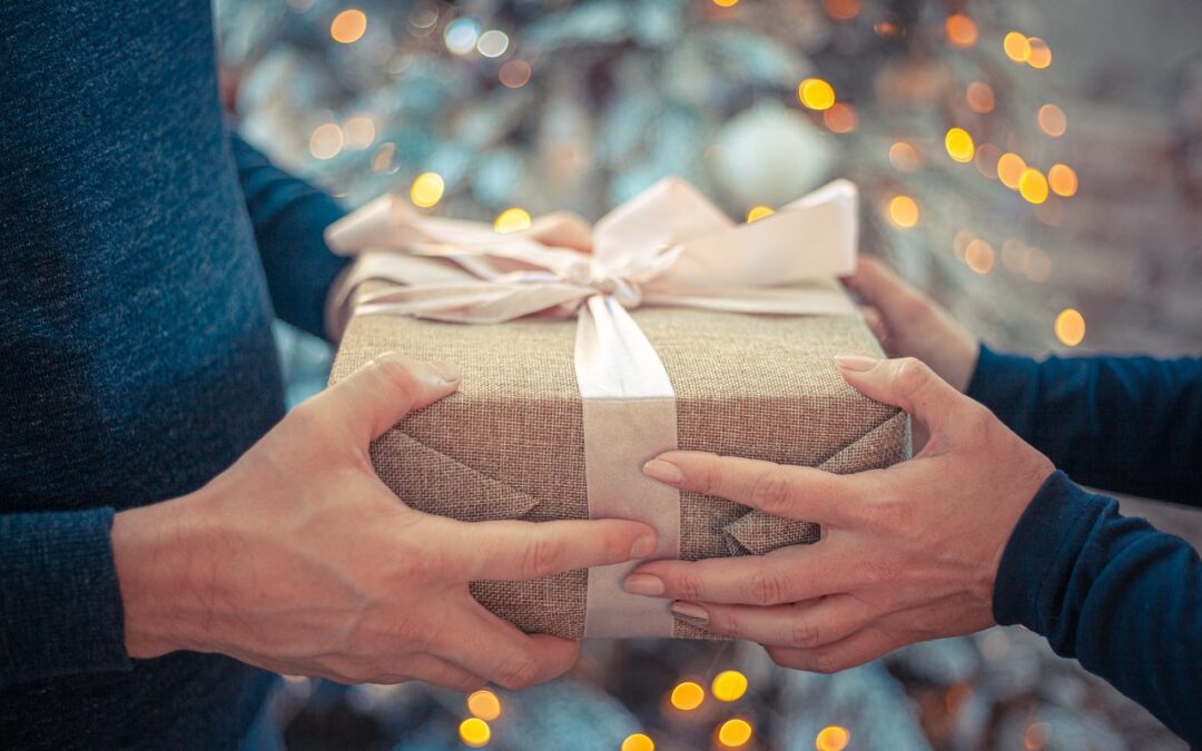 Photo of two hands exchanging a gift with a ribbon on it
